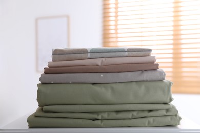 New clean folded bed linens on table indoors