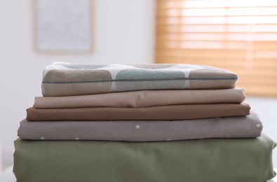 Photo of New clean folded bed linens on table indoors