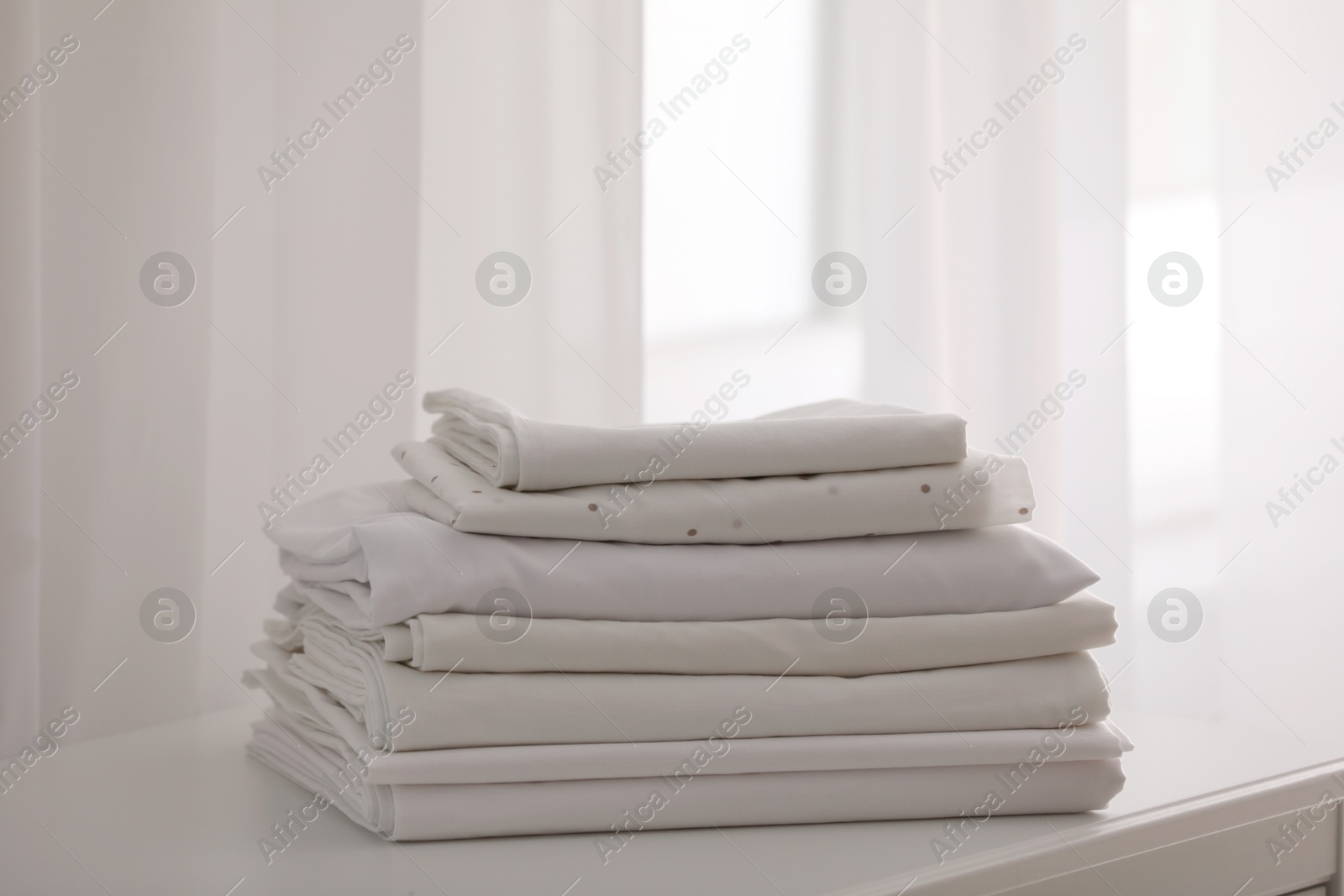 Photo of New clean folded linens on window sill indoors