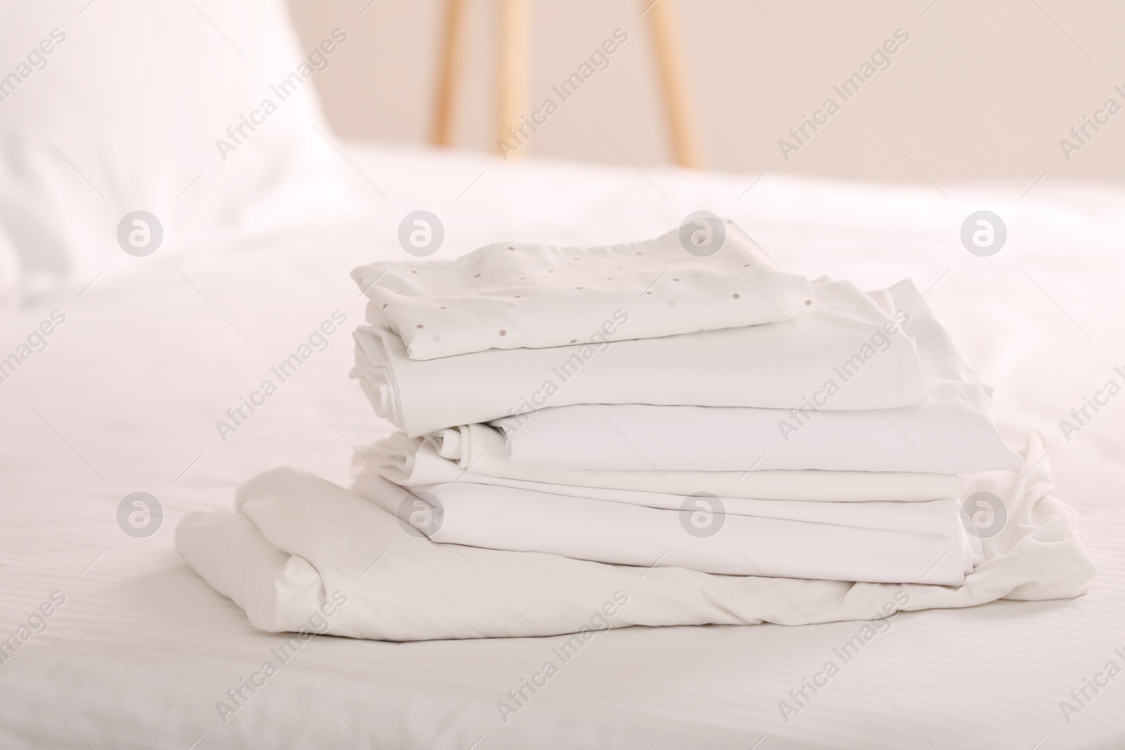 Photo of New clean folded linens on bed indoors