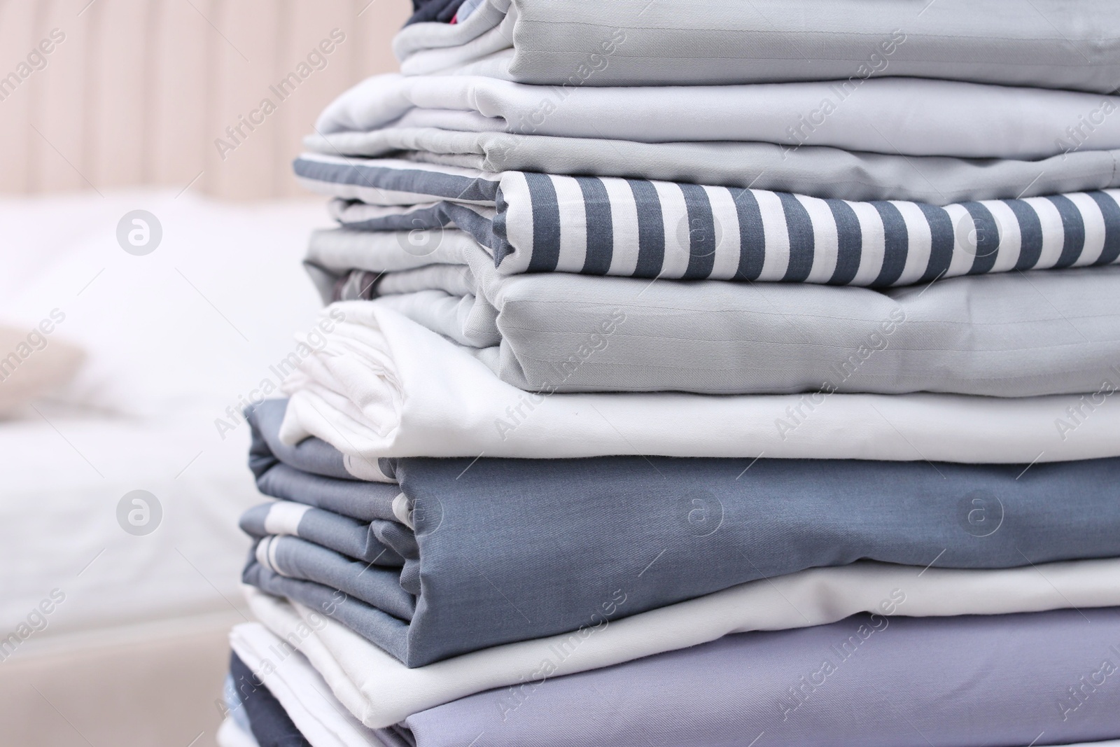 Photo of Stack of clean bed linens in bedroom, closeup. Space for text