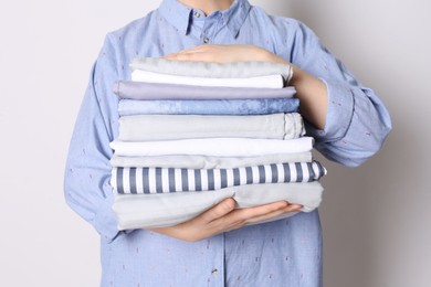 Photo of Woman holding stack of clean bed linens on white background, closeup