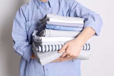 Photo of Woman holding stack of clean bed linens on white background, closeup