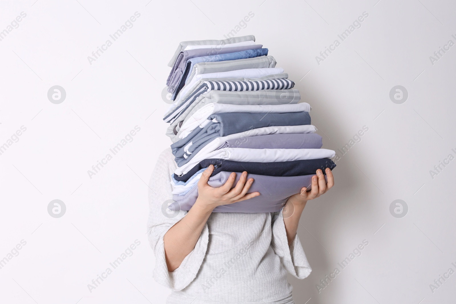 Photo of Woman holding stack of clean bed linens on white background