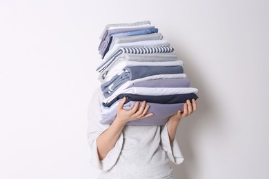 Woman holding stack of clean bed linens on white background