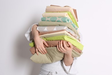 Photo of Woman holding stack of clean bed linens on white background