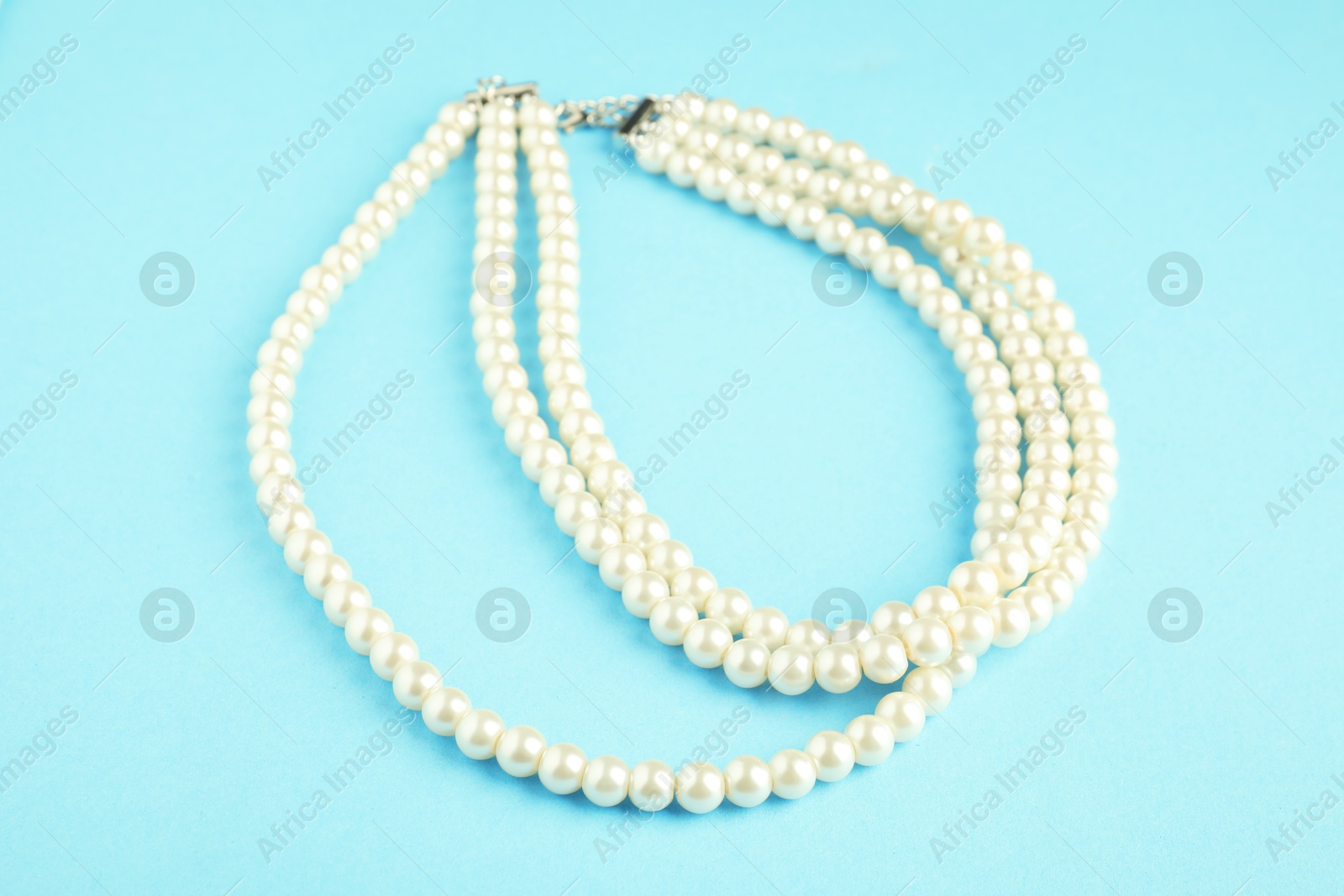 Photo of Beautiful bijouterie. Stylish necklace on light blue background, closeup