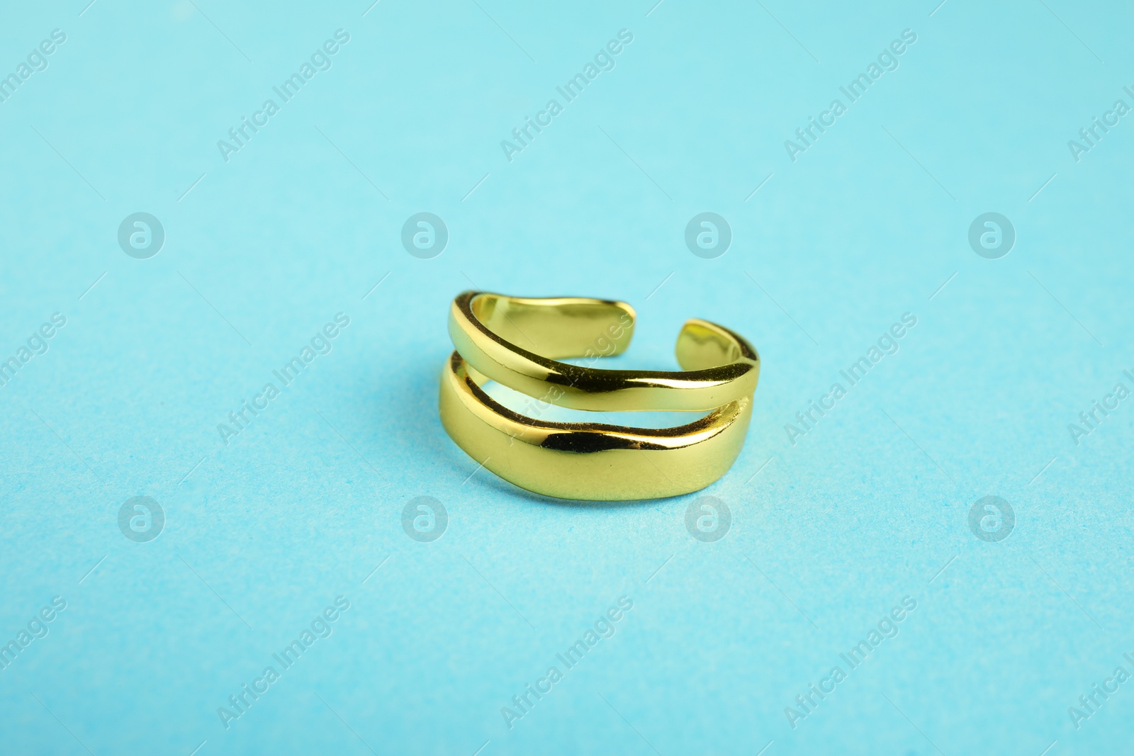 Photo of Beautiful bijouterie. Stylish ring on light blue background, closeup