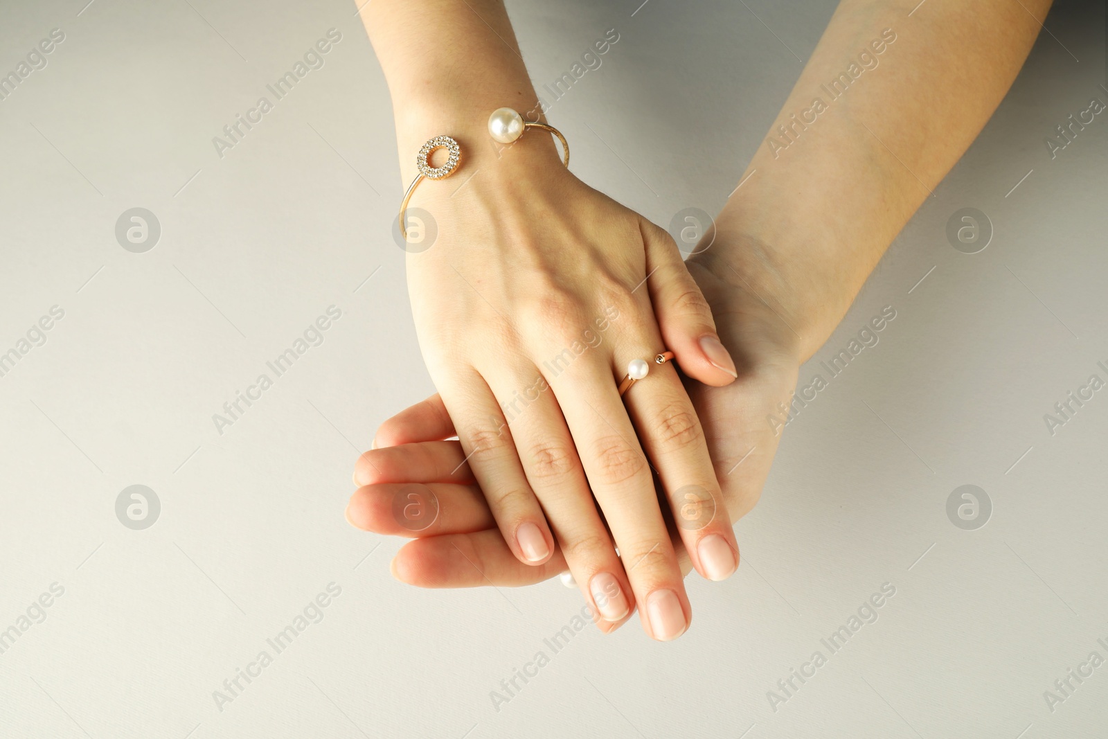 Photo of Beautiful bijouterie. Woman wearing stylish ring and bracelet on light grey background, top view