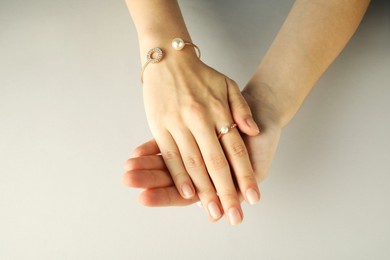 Photo of Beautiful bijouterie. Woman wearing stylish ring and bracelet on light grey background, top view