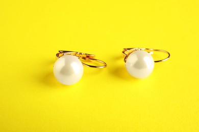 Photo of Beautiful bijouterie. Stylish earrings on yellow background, closeup