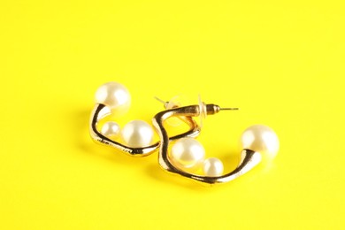 Photo of Beautiful bijouterie. Stylish earrings on yellow background, closeup