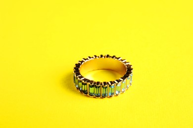 Photo of Beautiful bijouterie. Elegant ring on yellow background, closeup