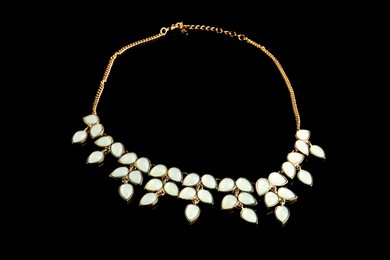 Photo of Beautiful bijouterie. Elegant necklace on black background, top view