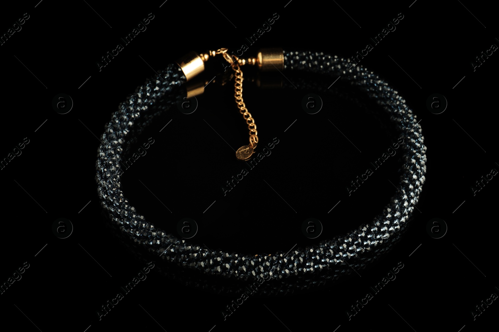 Photo of Beautiful bijouterie. Elegant bracelet on black mirror surface