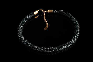 Photo of Beautiful bijouterie. Elegant bracelet on black mirror surface