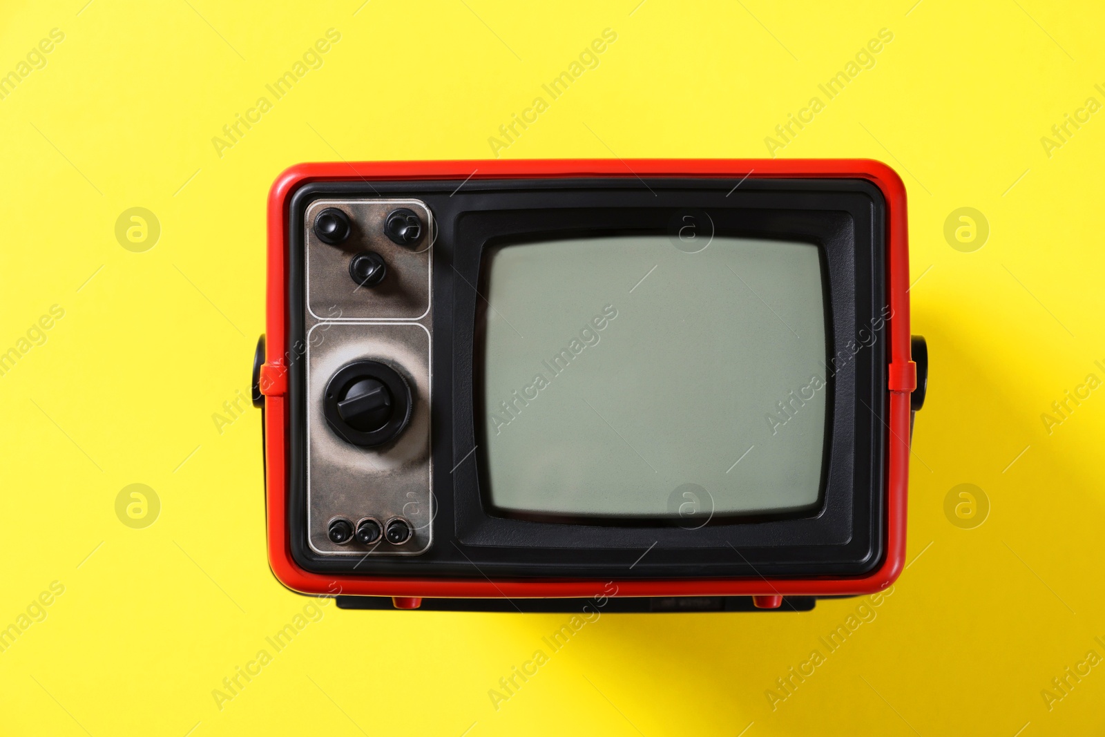 Photo of Retro tv set on yellow background, top view