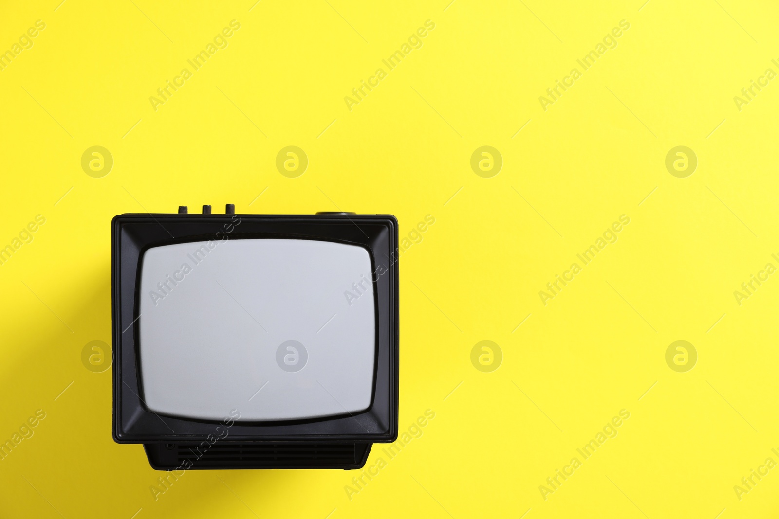 Photo of Retro tv set on yellow background, top view. Space for text