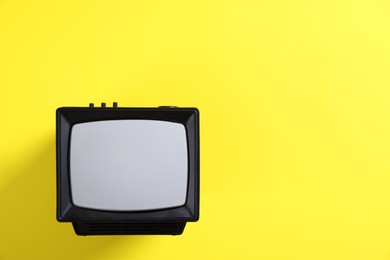 Retro tv set on yellow background, top view. Space for text