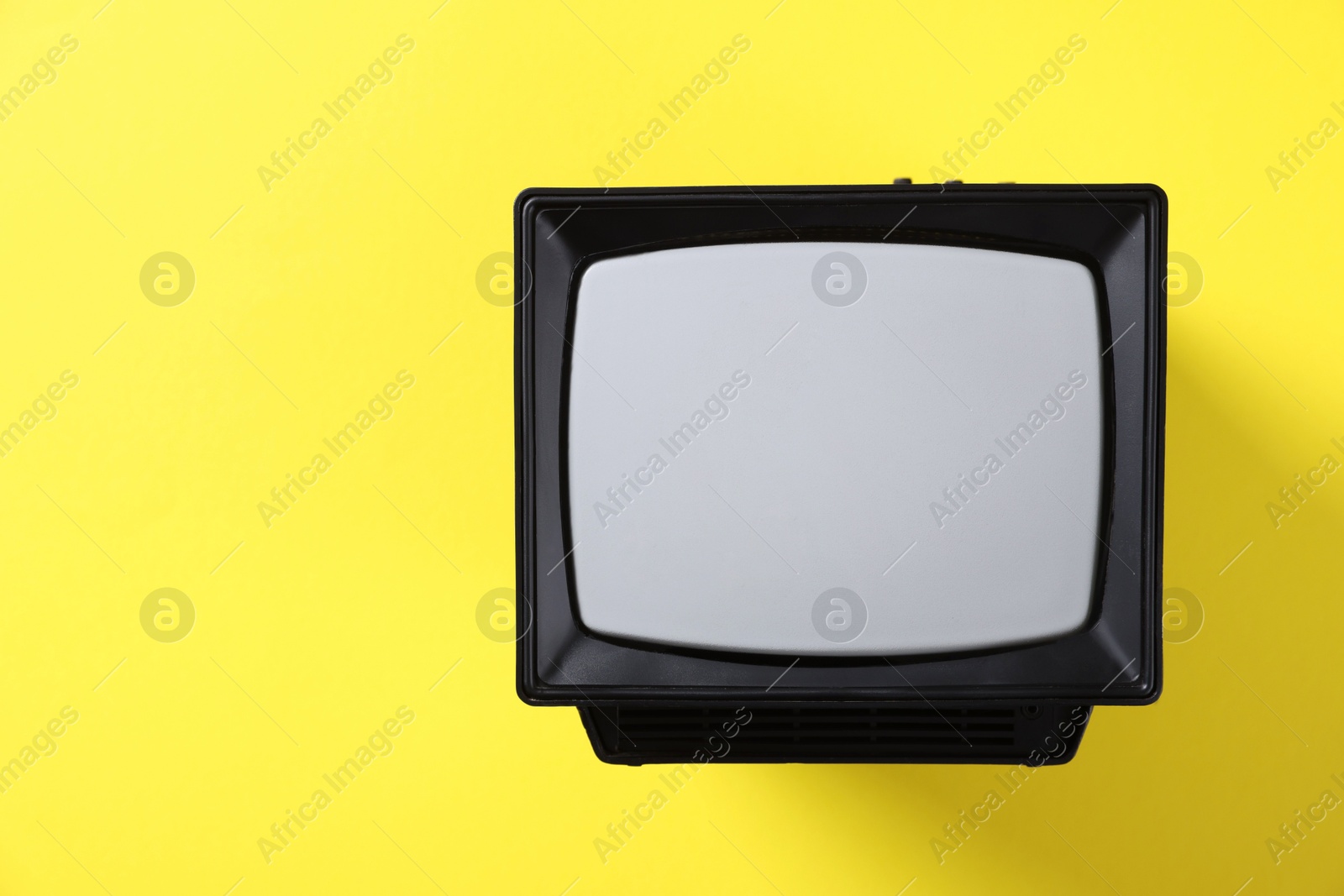 Photo of Retro tv set on yellow background, top view. Space for text