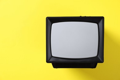 Photo of Retro tv set on yellow background, top view. Space for text