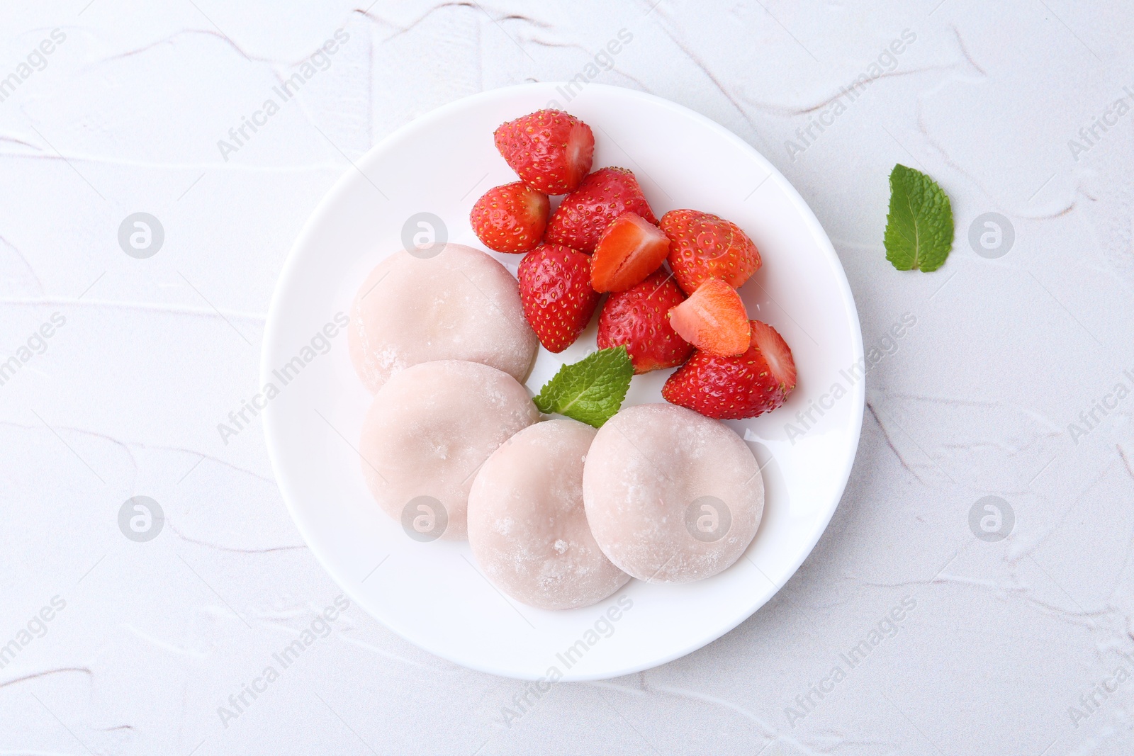 Photo of Delicious mochi and strawberries on white table, top view