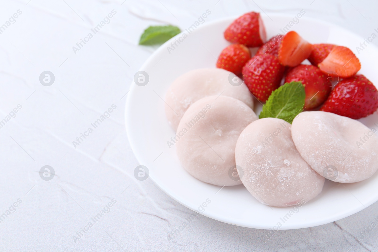 Photo of Delicious mochi and strawberries on white table, closeup