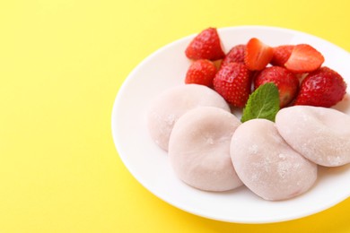 Photo of Delicious mochi and strawberries on yellow background, closeup