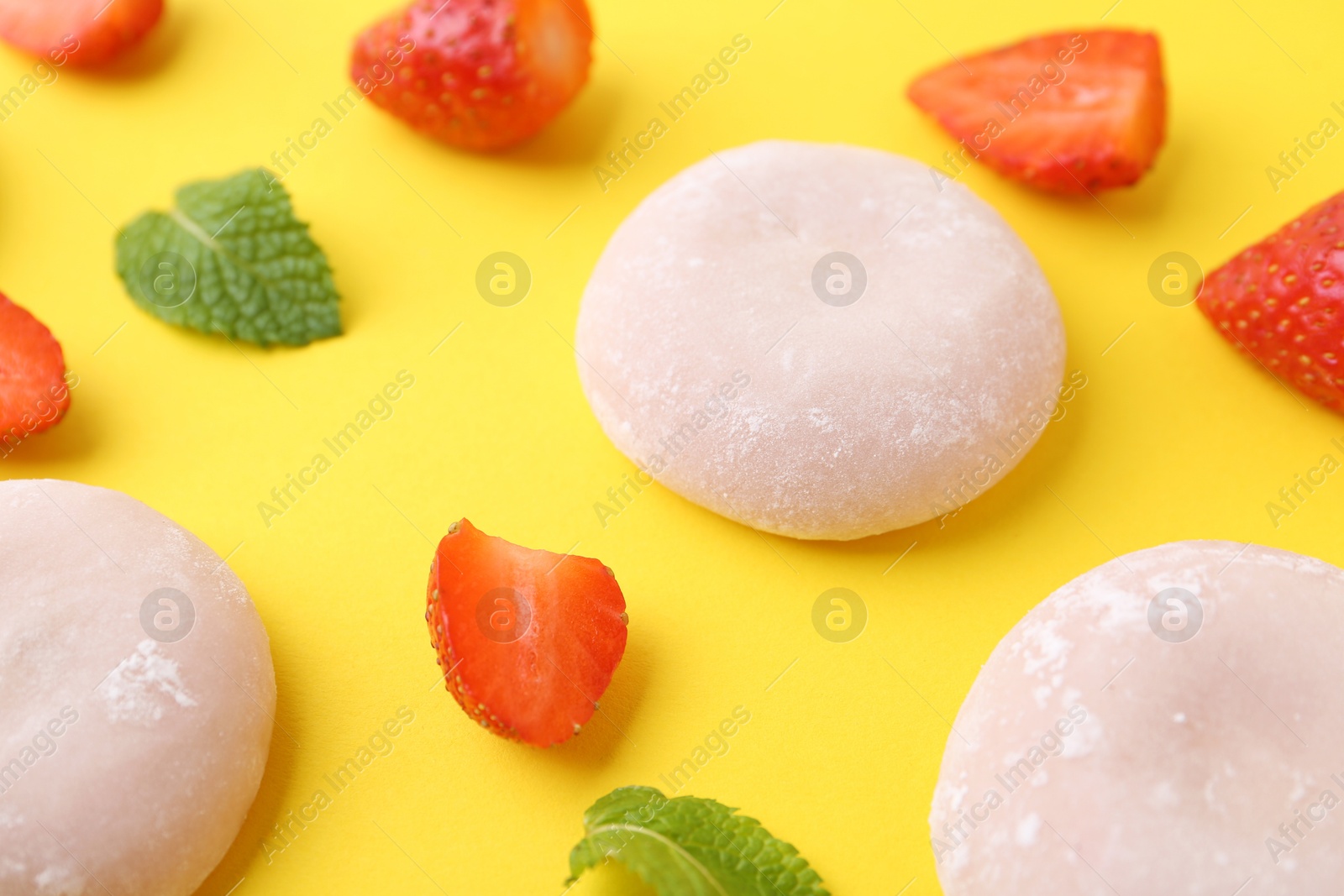 Photo of Delicious mochi and strawberries on yellow background, closeup