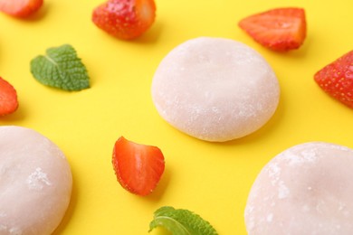 Photo of Delicious mochi and strawberries on yellow background, closeup