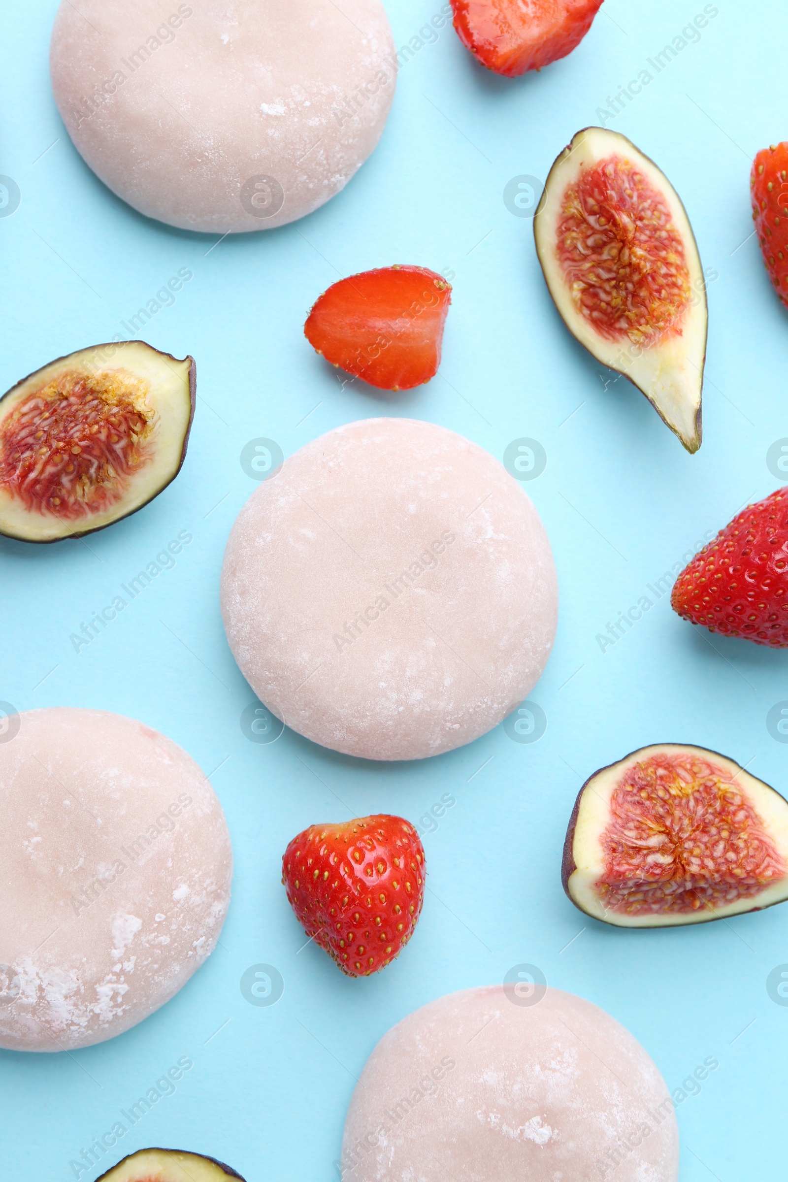 Photo of Delicious mochi, strawberries and figs on light blue background, flat lay