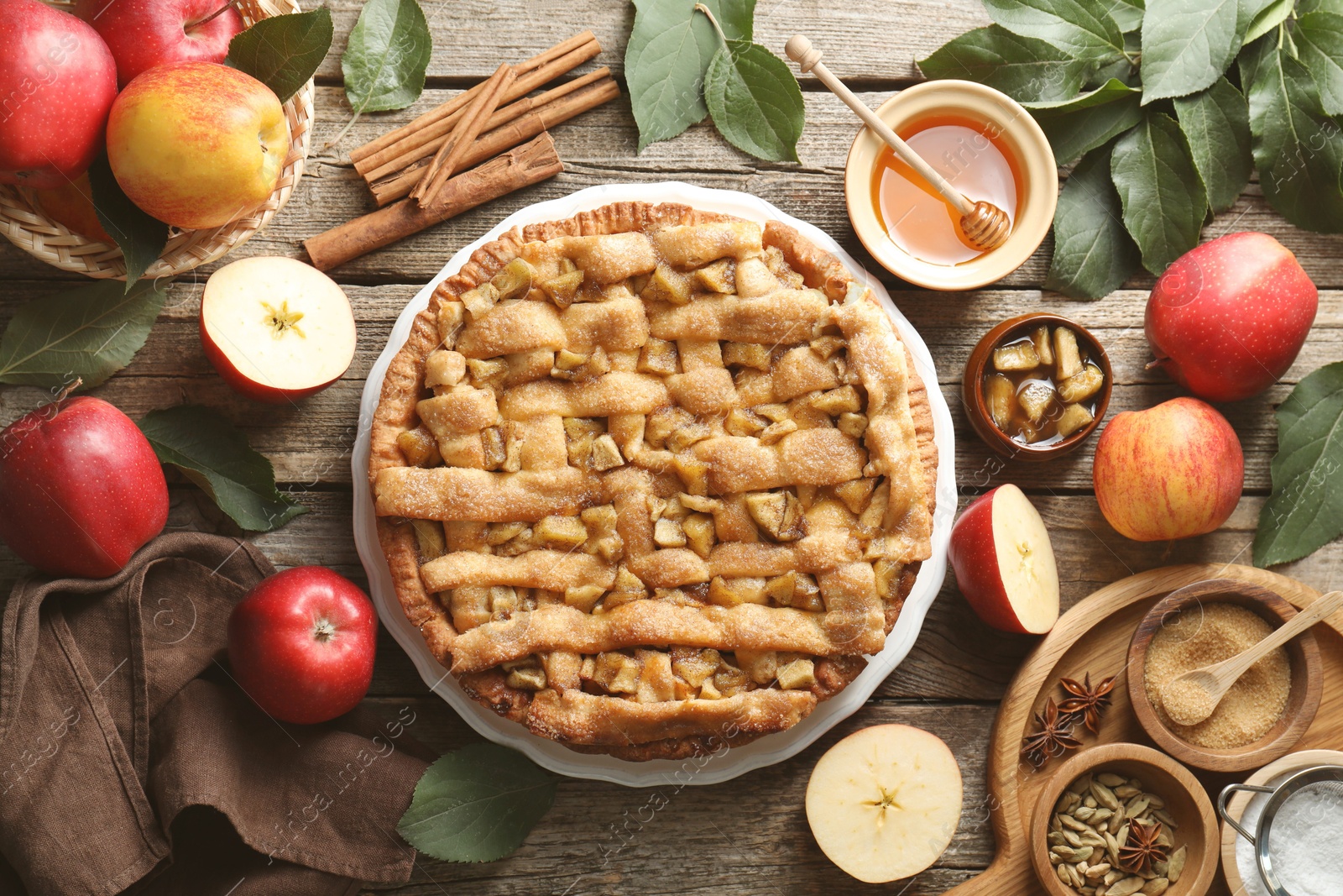 Photo of Homemade apple pie and ingredients on wooden table, flat lay