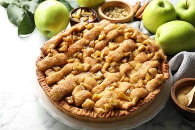 Photo of Homemade apple pie and ingredients on white marble table