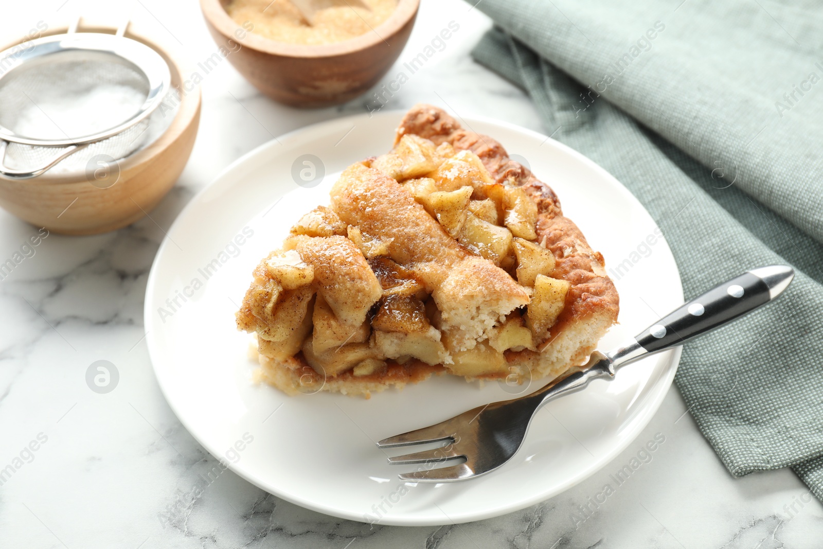 Photo of Slice of homemade apple pie and fork on white marble table