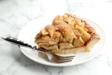 Photo of Slice of homemade apple pie and fork on white marble table