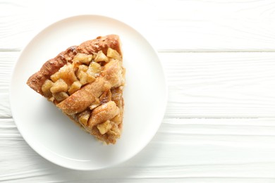 Photo of Slice of homemade apple pie on white wooden table, top view. Space for text