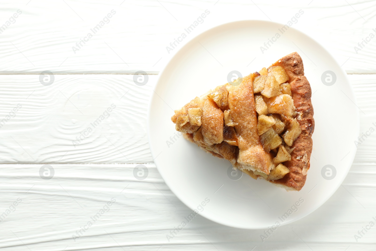 Photo of Slice of homemade apple pie on white wooden table, top view. Space for text