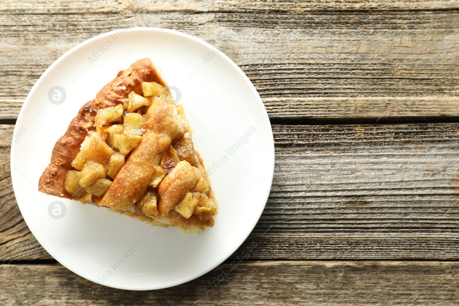 Photo of Slice of homemade apple pie on wooden table, top view. Space for text