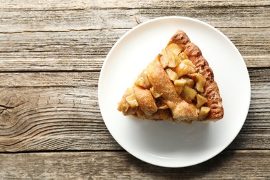 Photo of Slice of homemade apple pie on wooden table, top view. Space for text