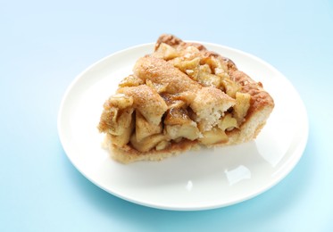 Photo of Slice of homemade apple pie on light blue background, closeup