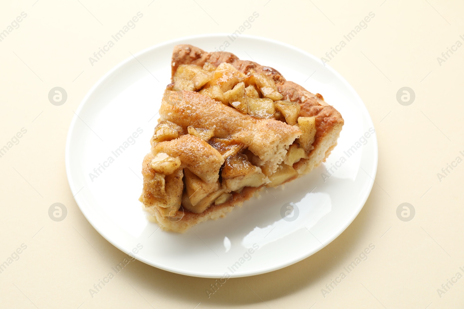 Photo of Slice of homemade apple pie on beige background, closeup