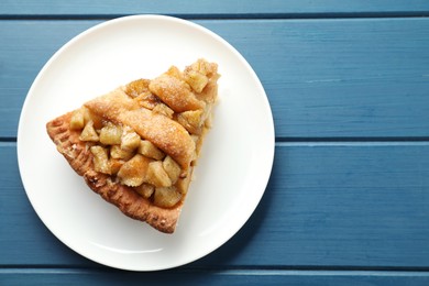 Photo of Slice of homemade apple pie on blue wooden table, top view. Space for text