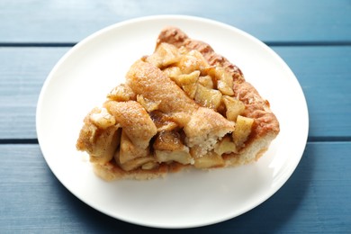 Photo of Slice of homemade apple pie on blue wooden table, closeup