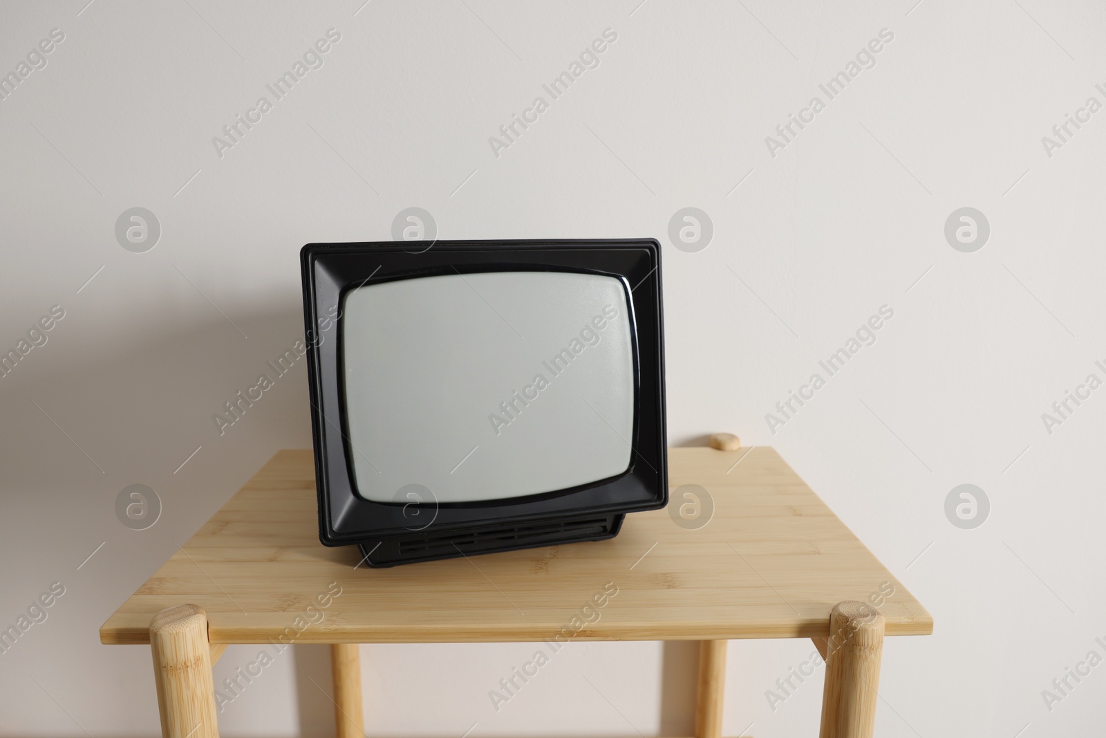 Photo of Retro tv set on wooden shelf against white wall