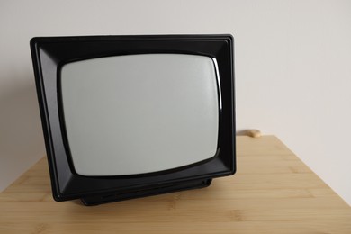 Photo of Retro tv set on wooden shelf against white wall