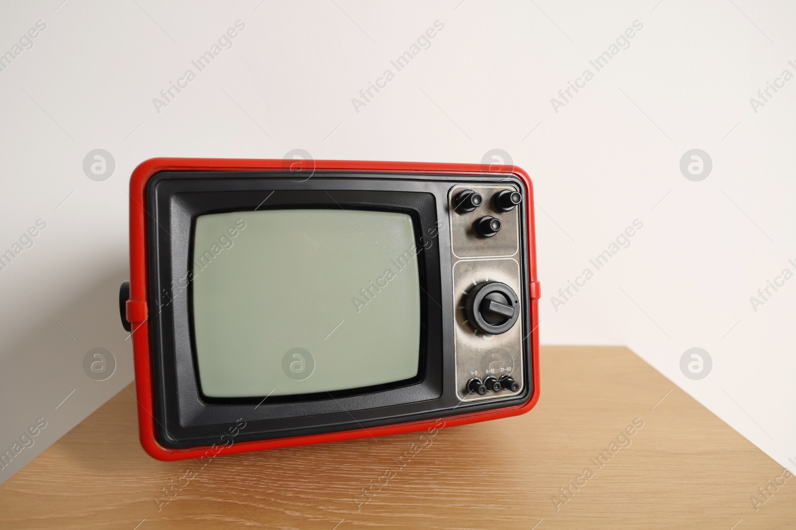 Photo of Retro tv set on nightstand against white wall