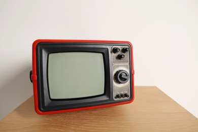 Photo of Retro tv set on nightstand against white wall