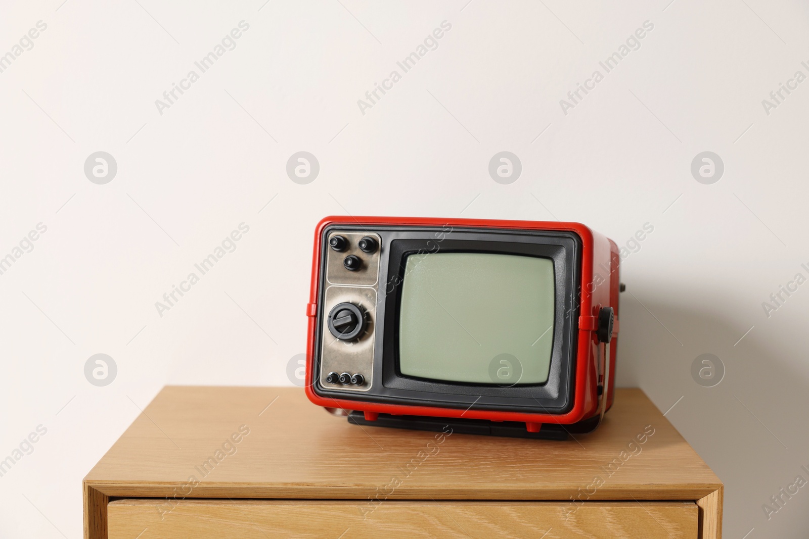 Photo of Retro tv set on nightstand against white wall