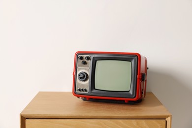 Photo of Retro tv set on nightstand against white wall