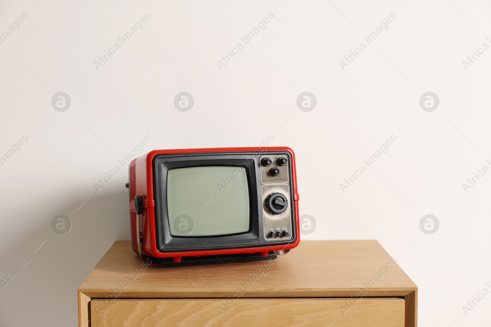 Photo of Retro tv set on nightstand against white wall